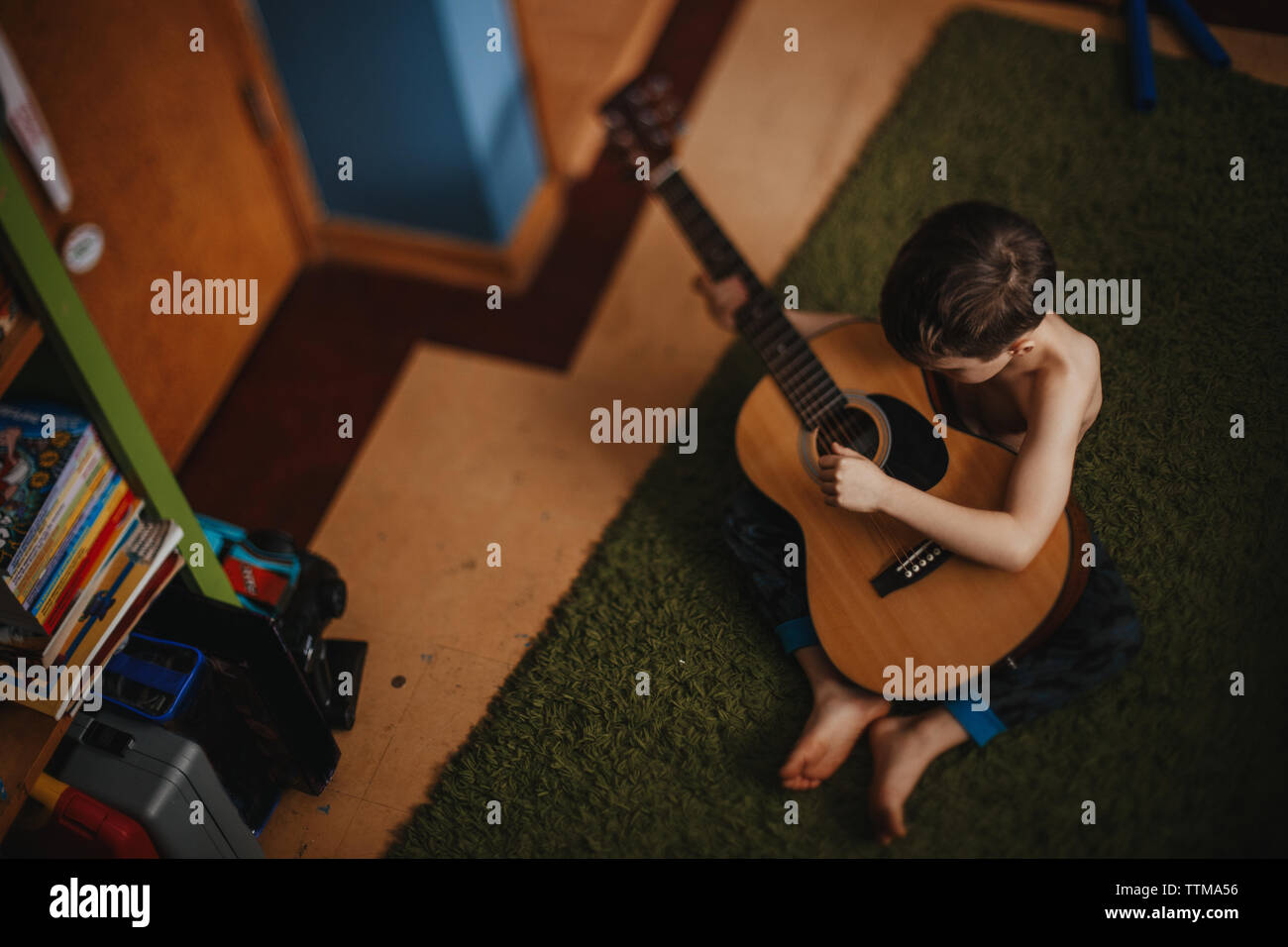 Un ragazzo svolge la sua chitarra tranquillamente nella sua stanza Foto Stock