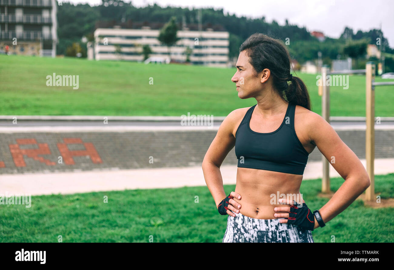 Premurosa donna con le mani sul hip guardando lontano rimanendo in posizione di parcheggio Foto Stock