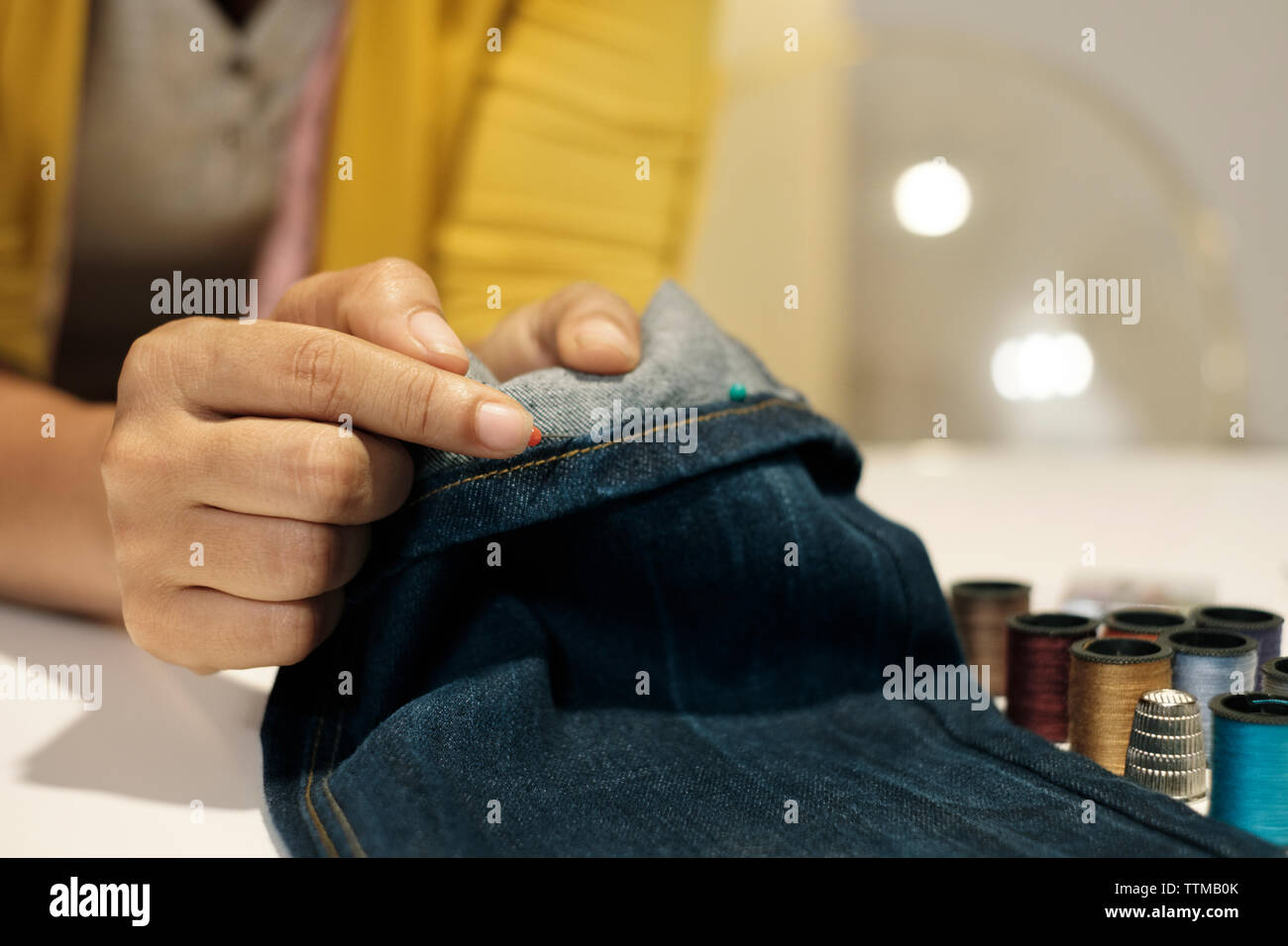 Sezione mediana di imprenditore femmina holding jeans sulla tavola in ufficio Foto Stock