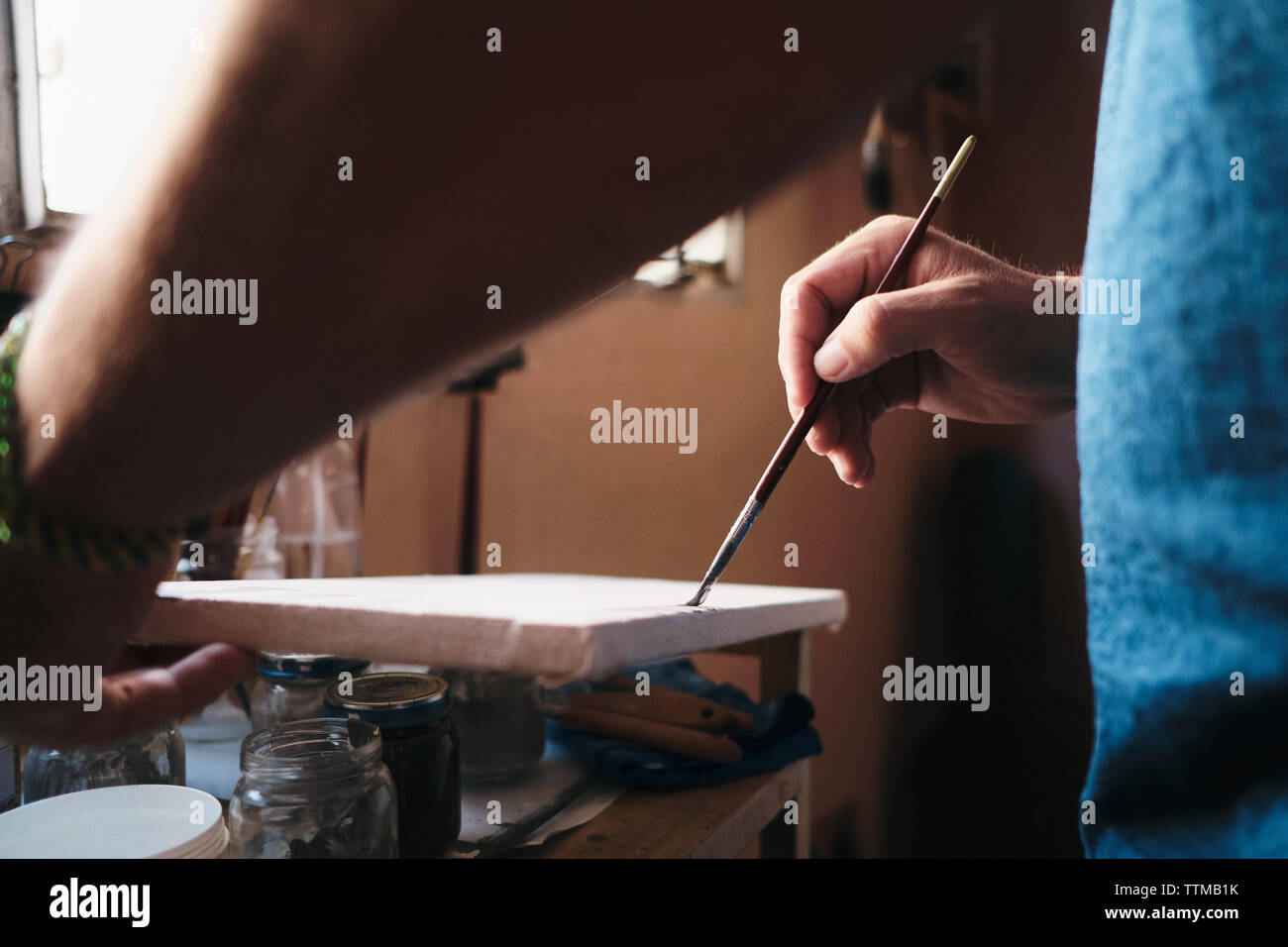 Artista maschile test di vernice acrilica e pennello su tela per il nuovo lavoro Foto Stock