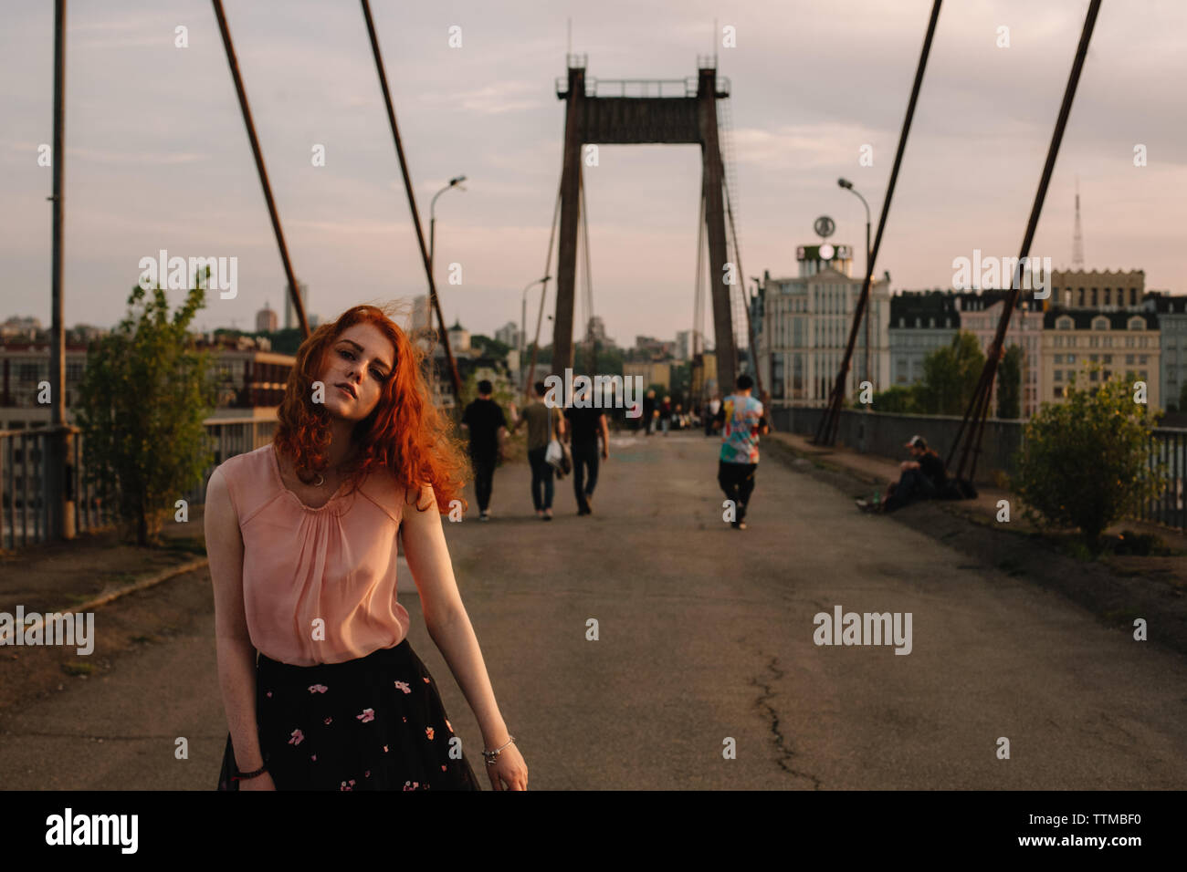 La ragazza con i capelli rossi camminando sul ponte in città Foto Stock