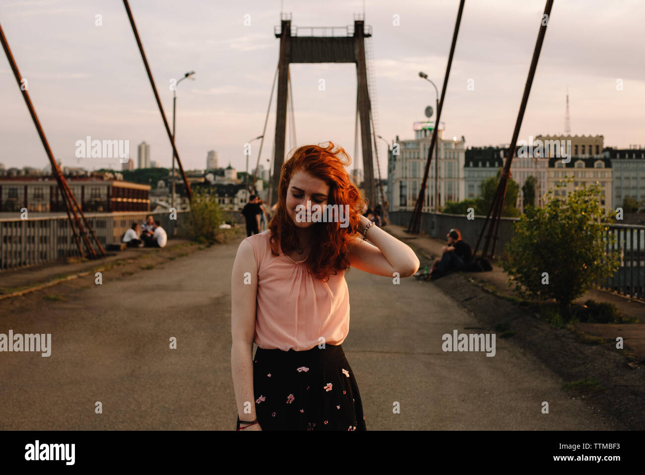 Ritratto di sorridere redhead donna in piedi sul ponte in città Foto Stock