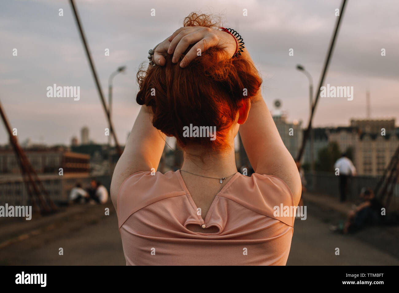 Vista posteriore del redhead donna tenendo i capelli mentre si sta in piedi sul ponte Foto Stock