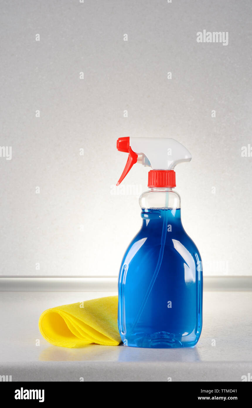Detergente per vetri con un panno per la pulizia sul tavolo grigio Foto Stock