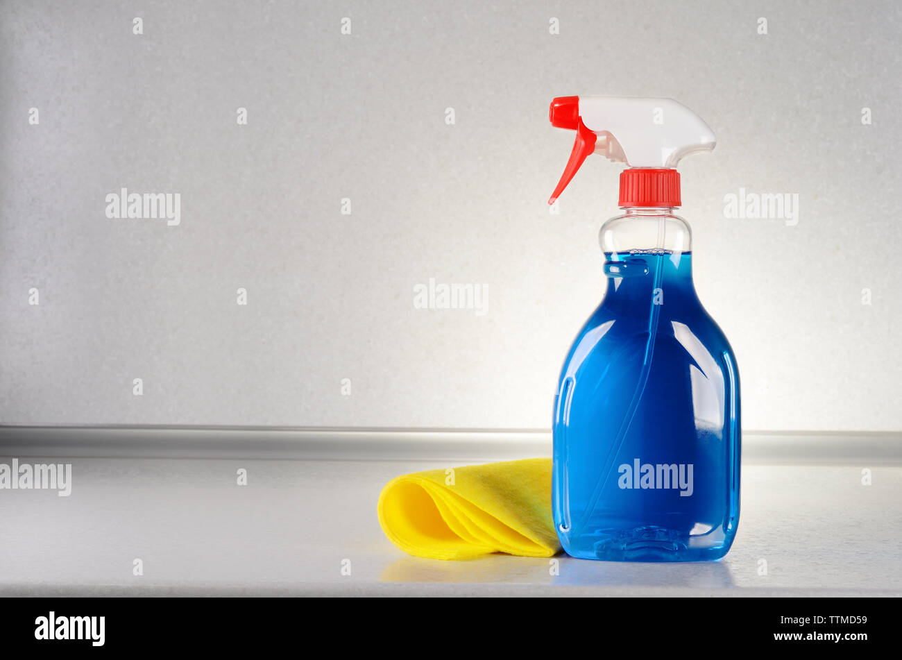 Detergente per vetri con un panno per la pulizia sul tavolo grigio Foto Stock