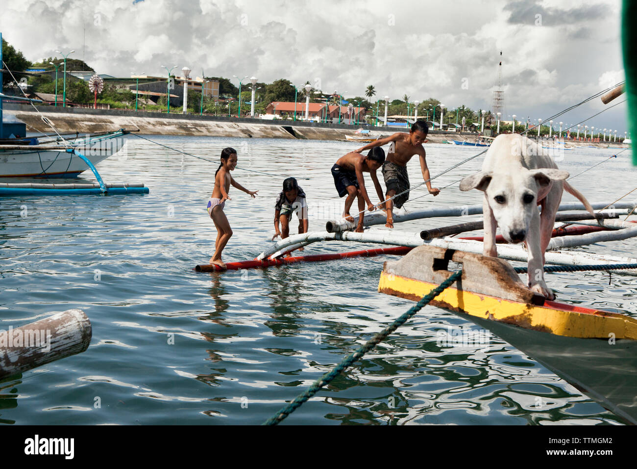 Filippine, Palawan Puerto Princesa, bambini giocano su imbarcazioni da pesca in città Area portuale Foto Stock