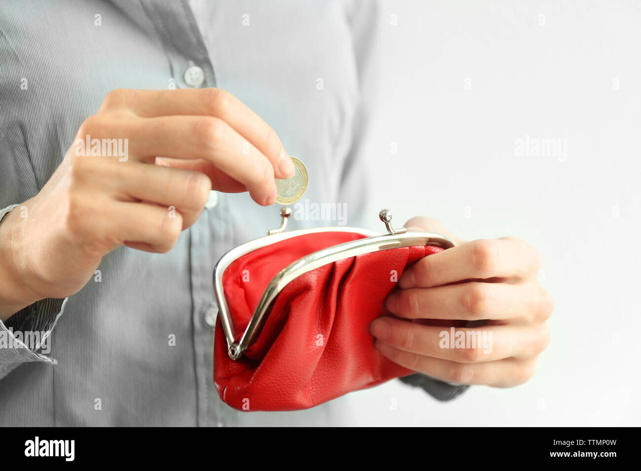 Donna mettendo moneta nella borsa di colore rosso Foto Stock