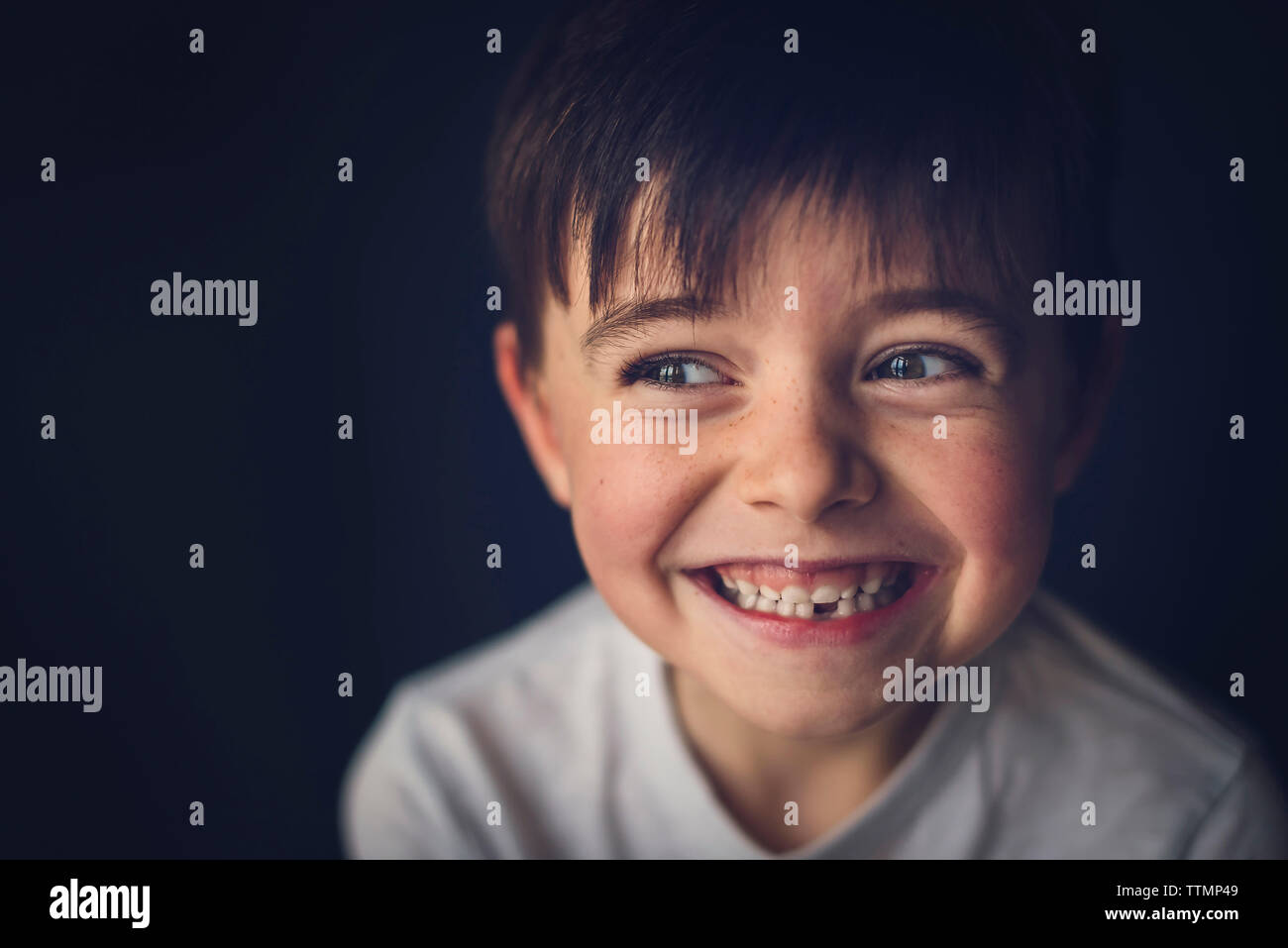 Allegro ragazzo con gap cercando dentata lontano nella camera oscura Foto Stock