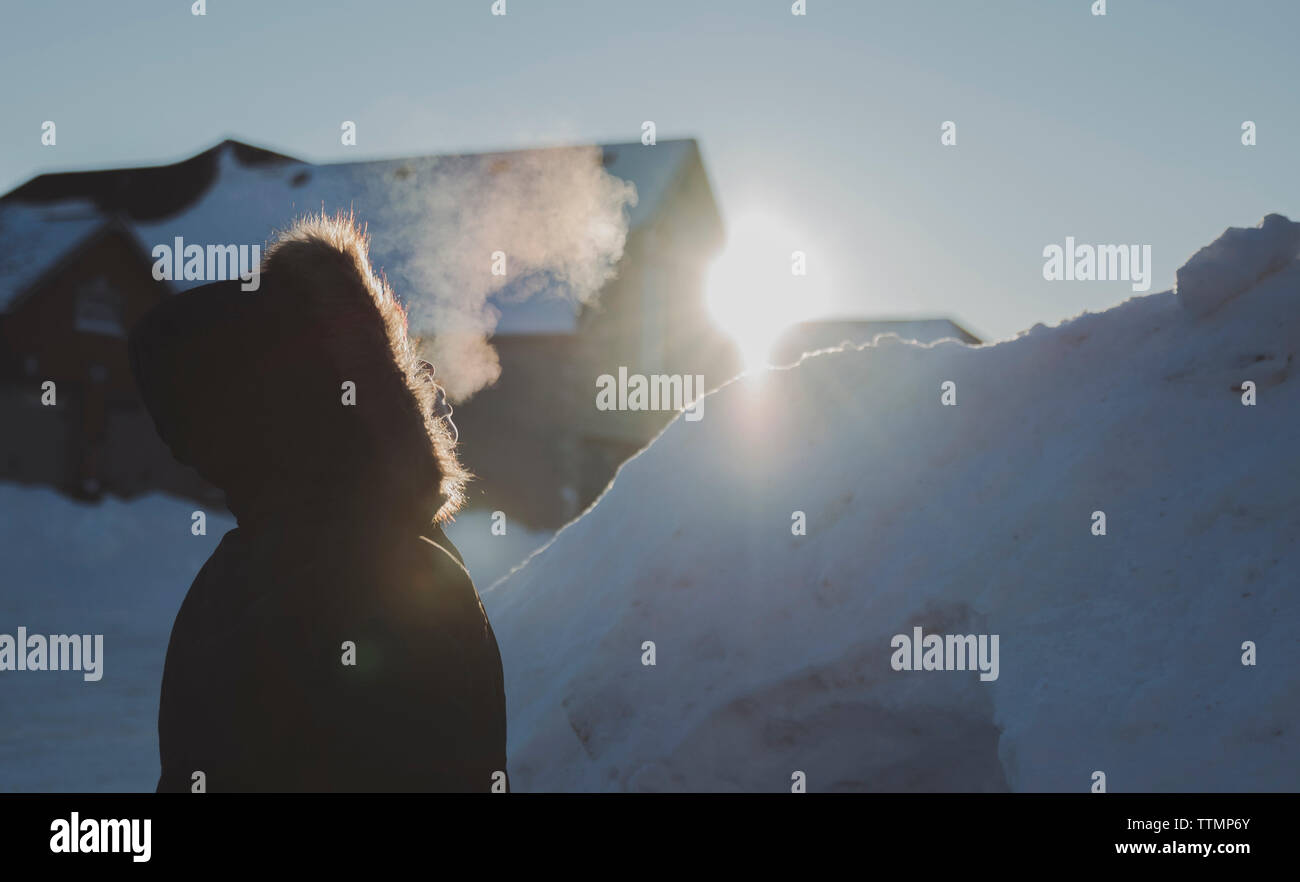 Vista laterale del ragazzo che indossa pelliccia permanente, mentre all'aperto durante la stagione invernale Foto Stock