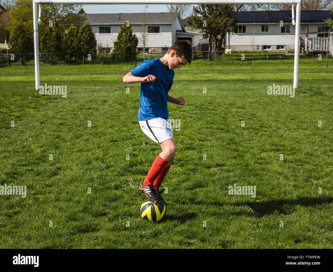 Lunghezza completa di ragazzo giocando con il pallone da calcio sul campo Foto Stock