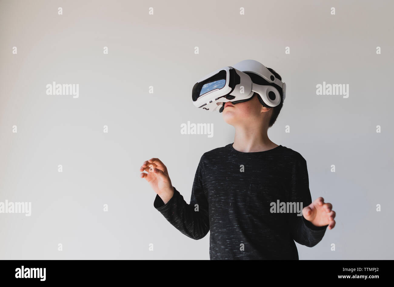 Boy utilizzando la realtà virtuale contro uno sfondo bianco Foto Stock