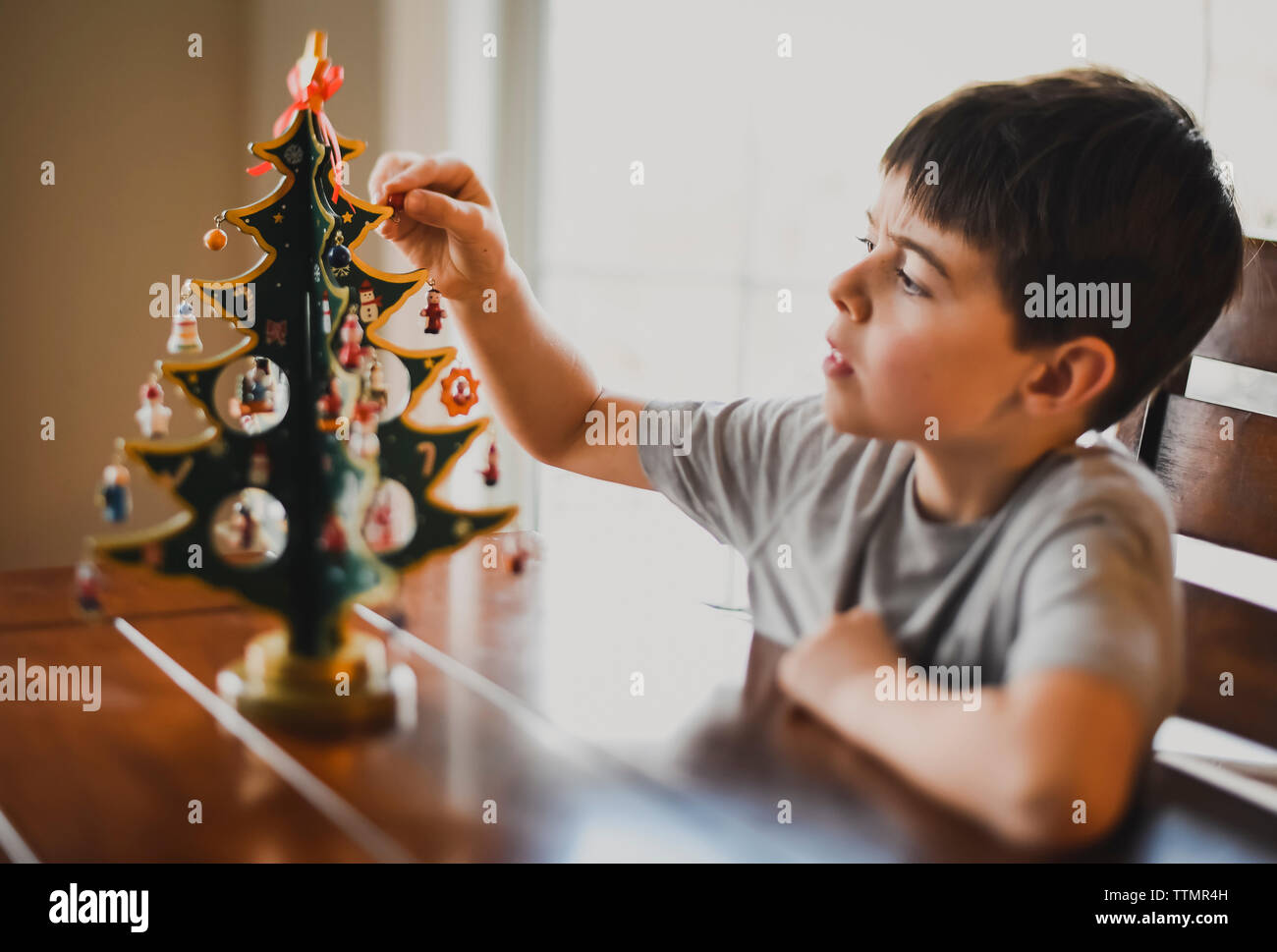 Ragazzo che guarda da vicino al tavolo di legno top albero di Natale. Foto Stock