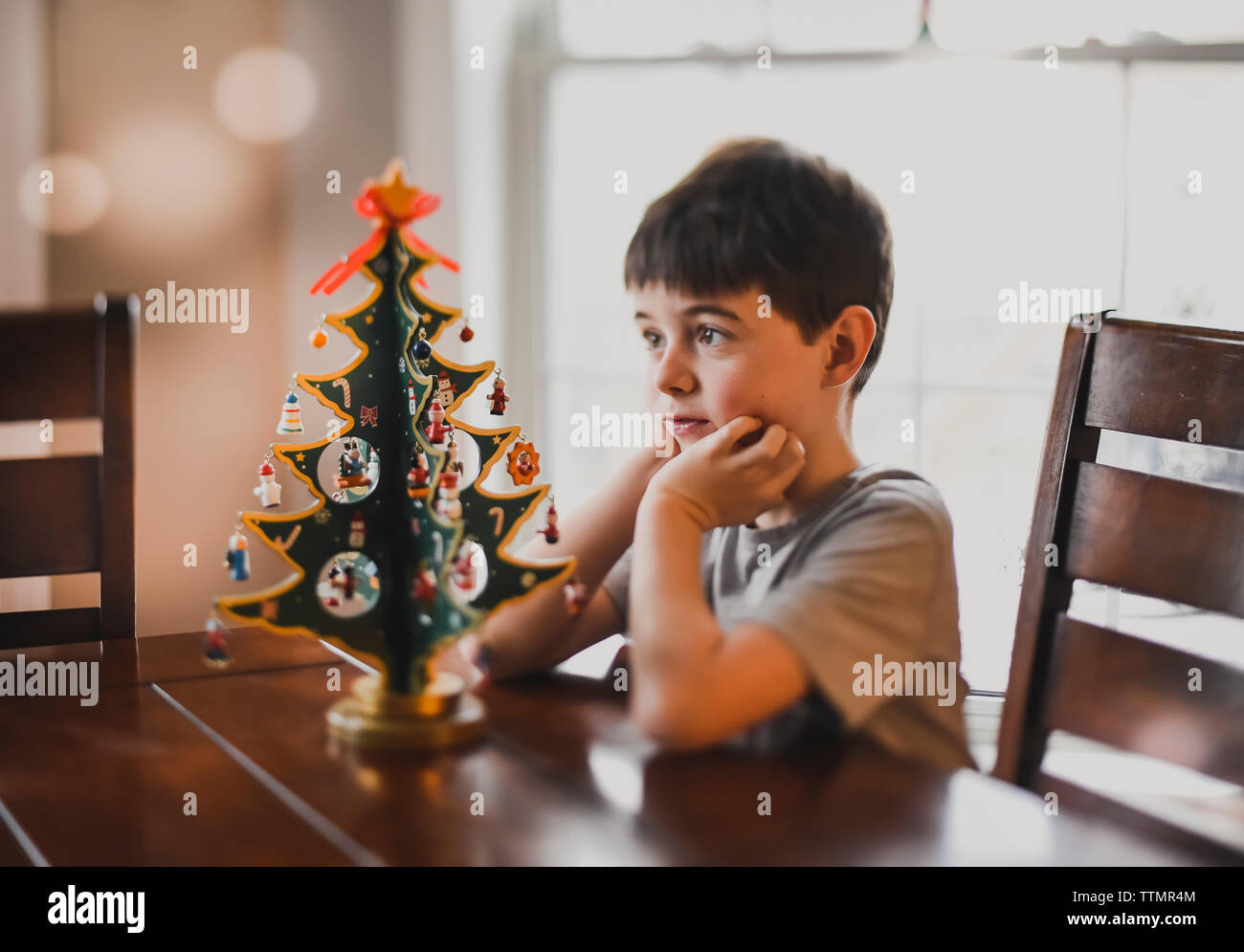 Ragazzo che guarda da vicino al tavolo di legno top albero di Natale. Foto Stock