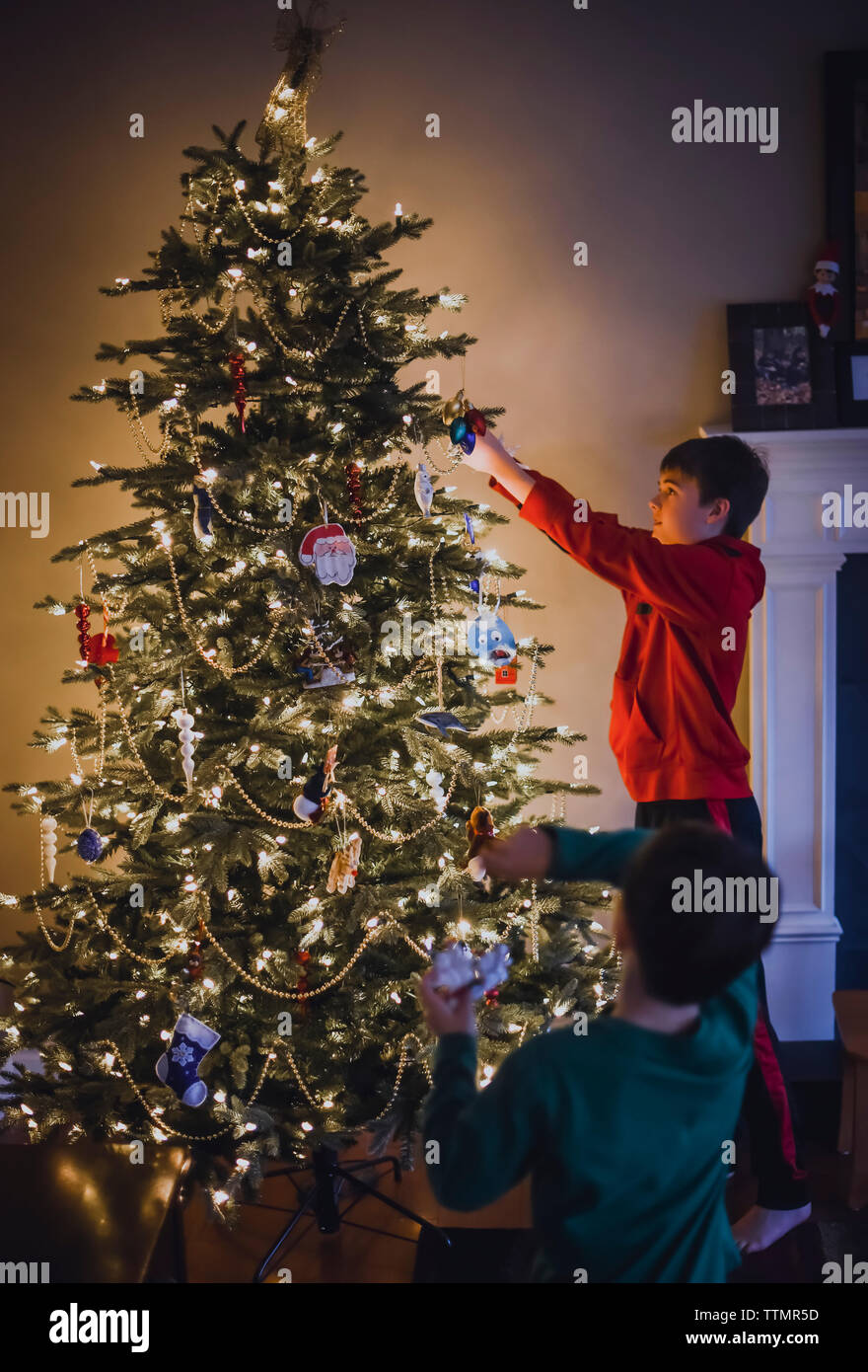 Due ragazzi decorare l'albero di Natale insieme. Foto Stock