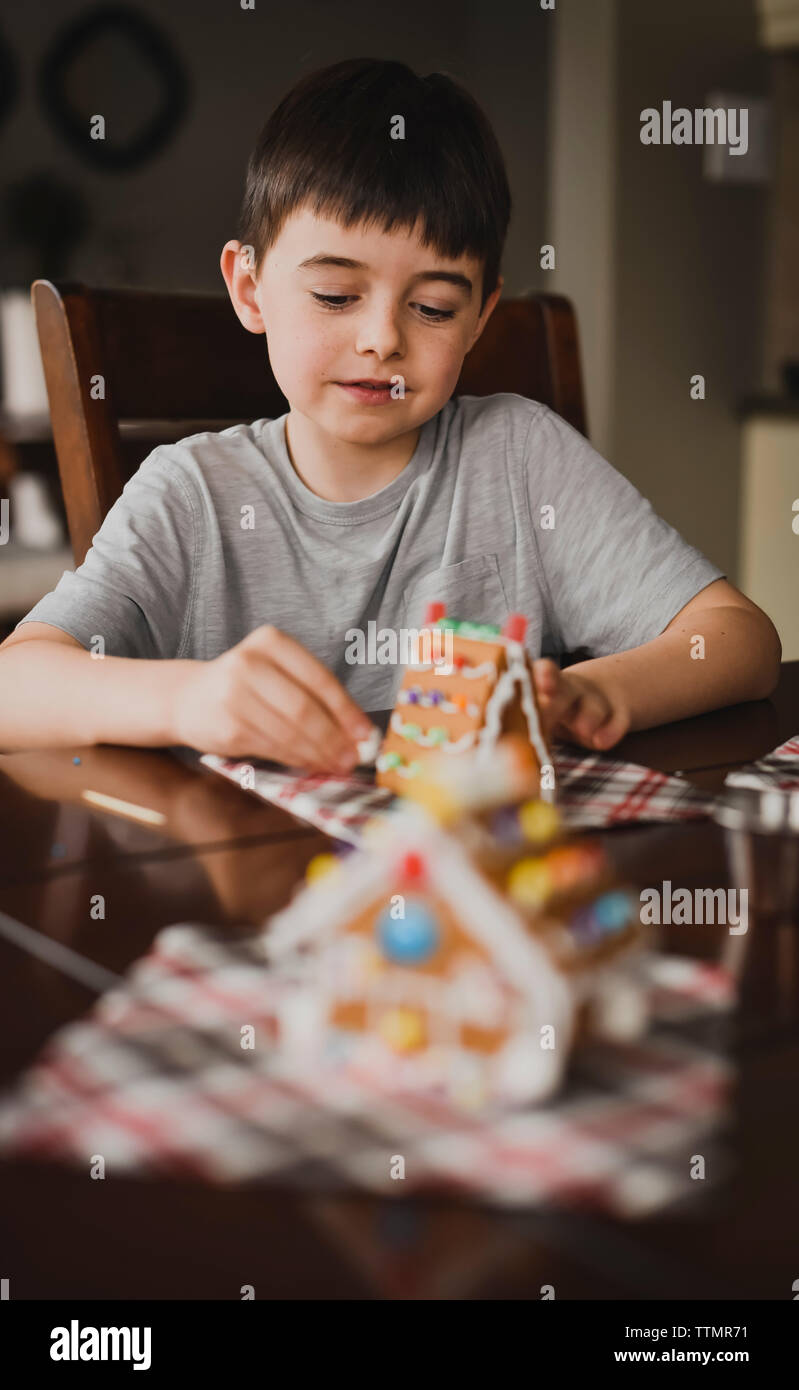 Giovane ragazzo caramelle mettendo su una casa di panpepato. Foto Stock