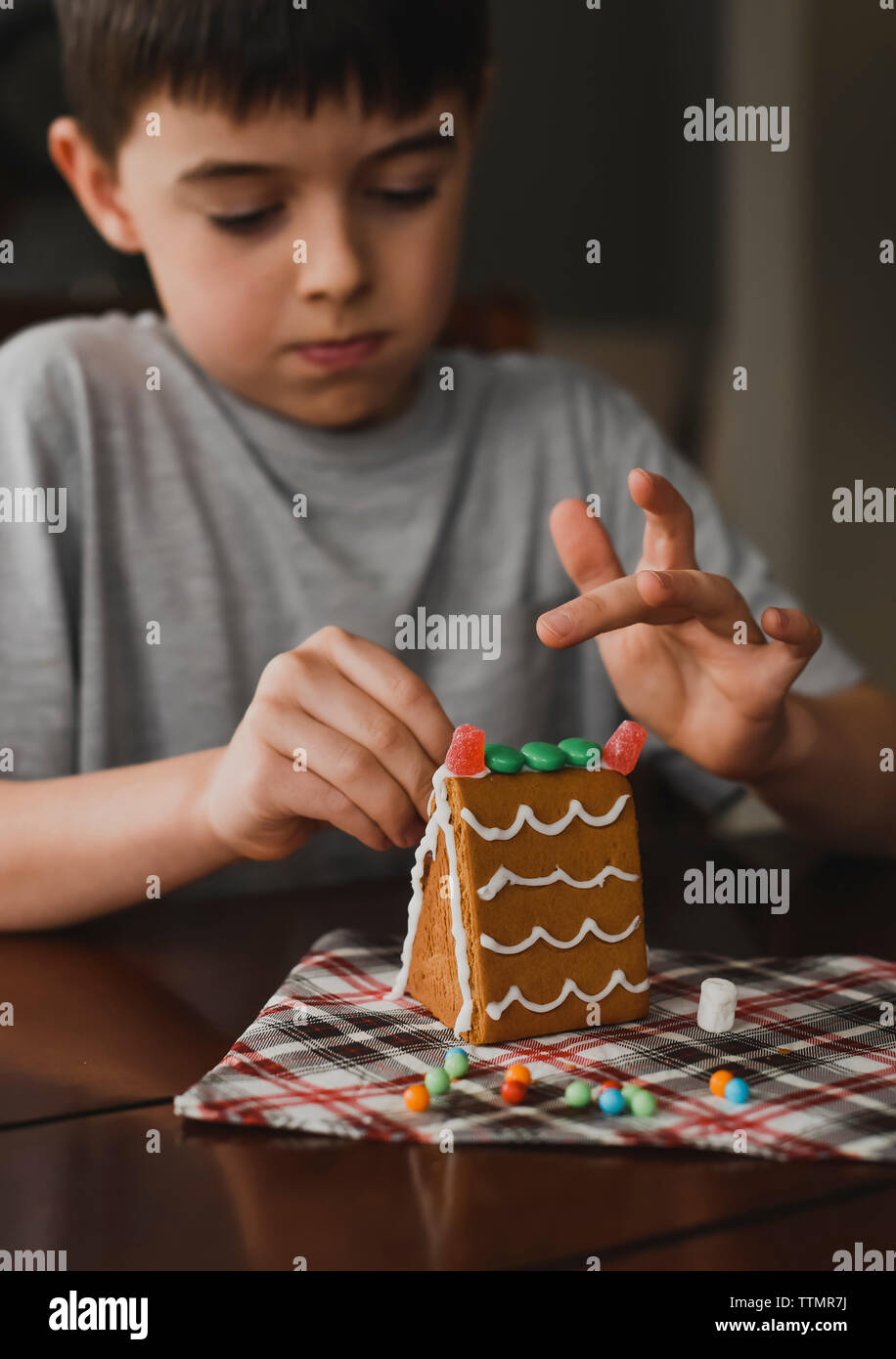 Chiusura del giovane ragazzo caramelle mettendo su una casa di panpepato. Foto Stock