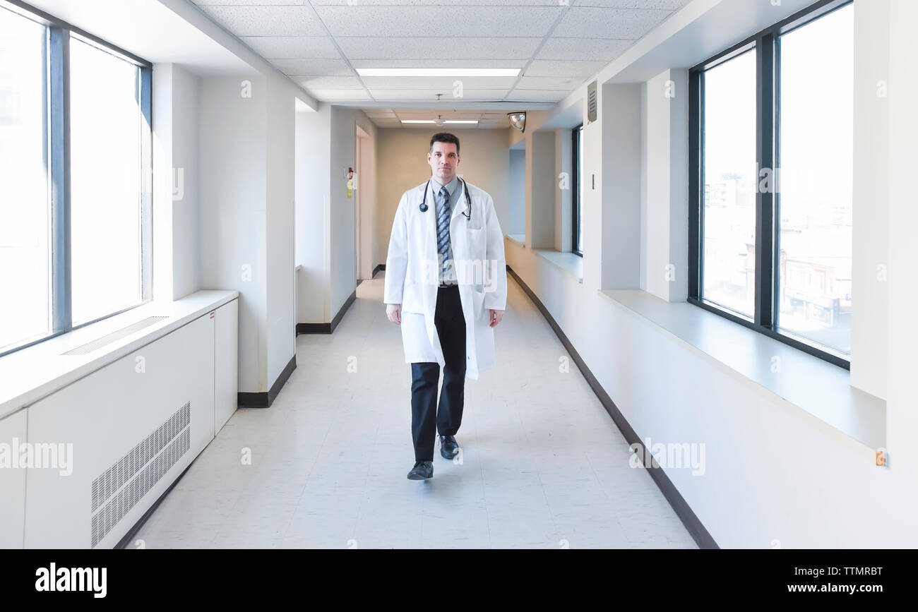 Dottore in camice bianco a camminare per il corridoio in un ospedale. Foto Stock