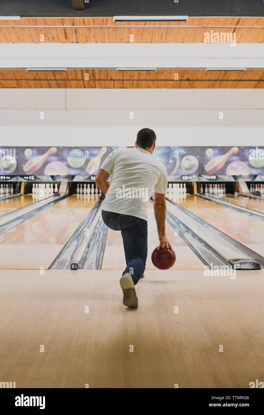 L'uomo gettando bowling con la sfera verso il basso una corsia a una pista da bowling. Foto Stock