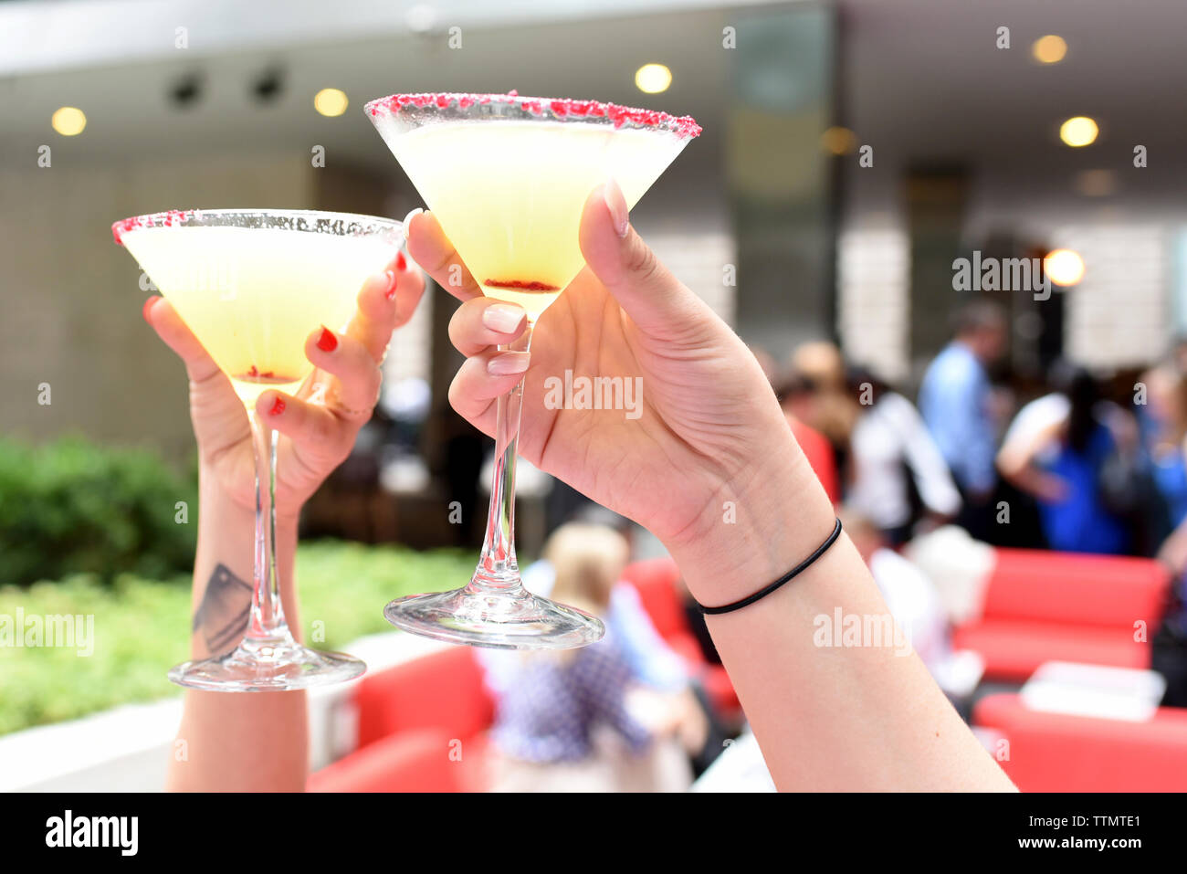 Mani tagliate di amici di sesso femminile la tostatura bicchieri da martini al ristorante Foto Stock