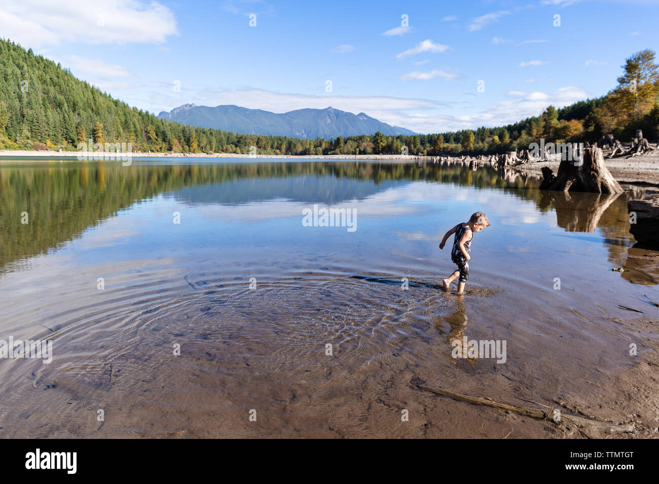 Ragazzo passeggiate in montagna lago in una giornata con cielo azzurro e sole Foto Stock