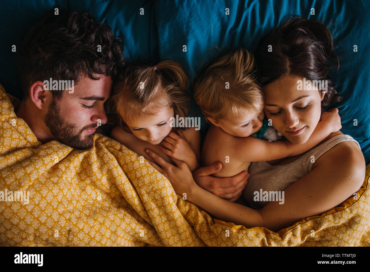 Famiglia di quattro coccole a letto con i bambini Foto Stock