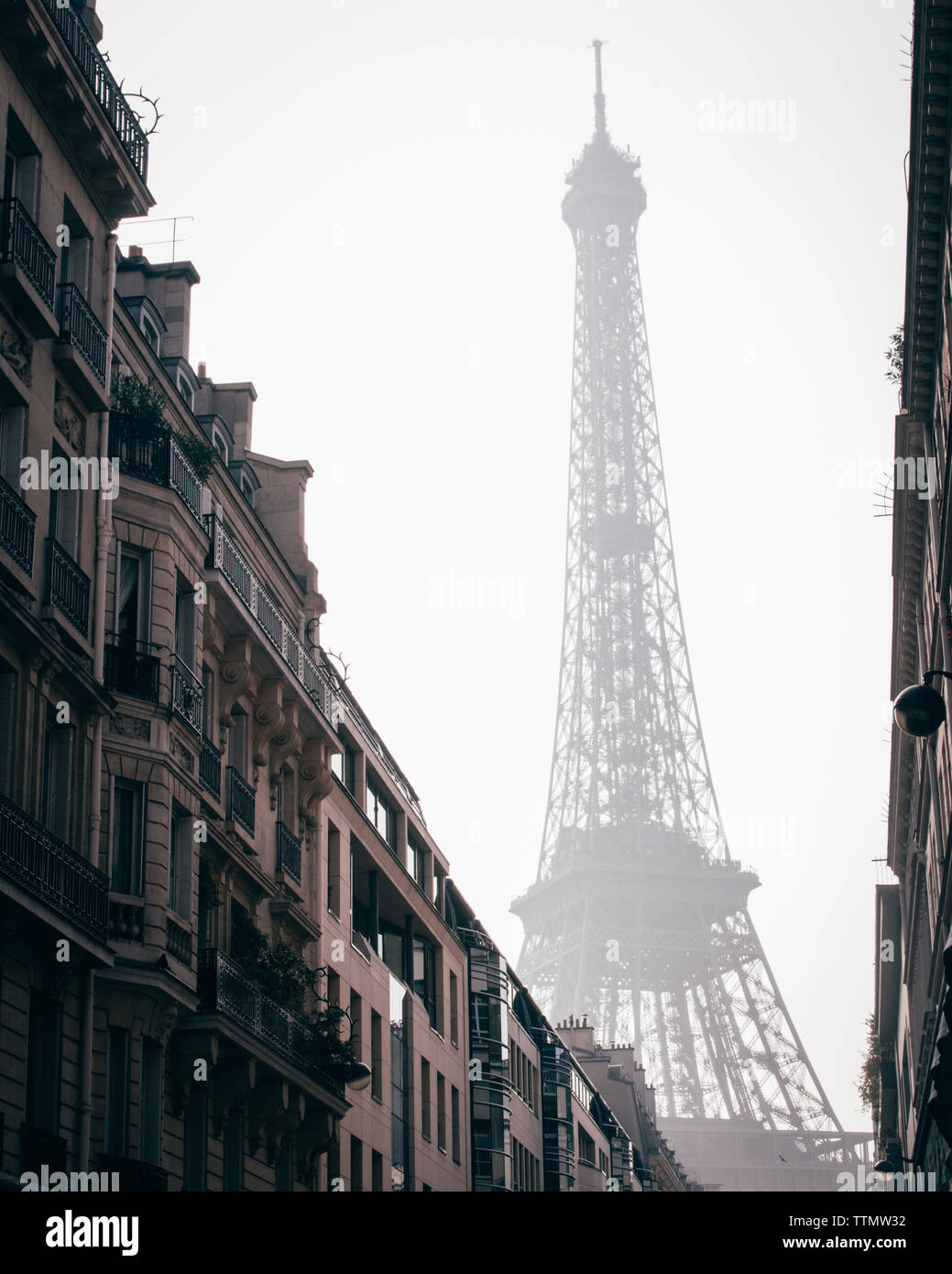 Basso angolo vista della Torre Eiffel contro il cielo in città durante la nebbia meteo Foto Stock