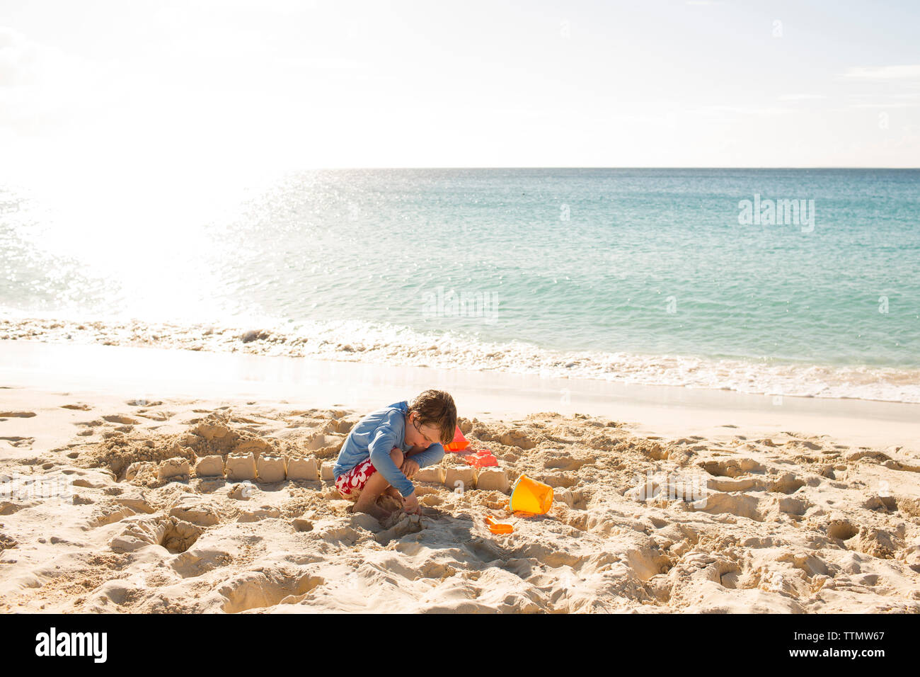 Ragazzo che sandcastle a beach contro sky sulla giornata di sole Foto Stock