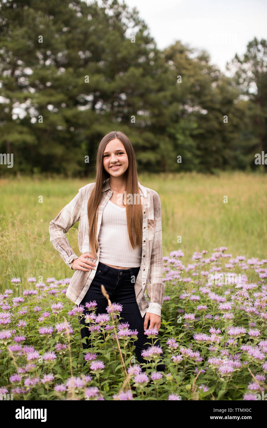 Macchina fotografica consapevole, sorridente, Teen Girl sorge in un campo di fiori viola Foto Stock