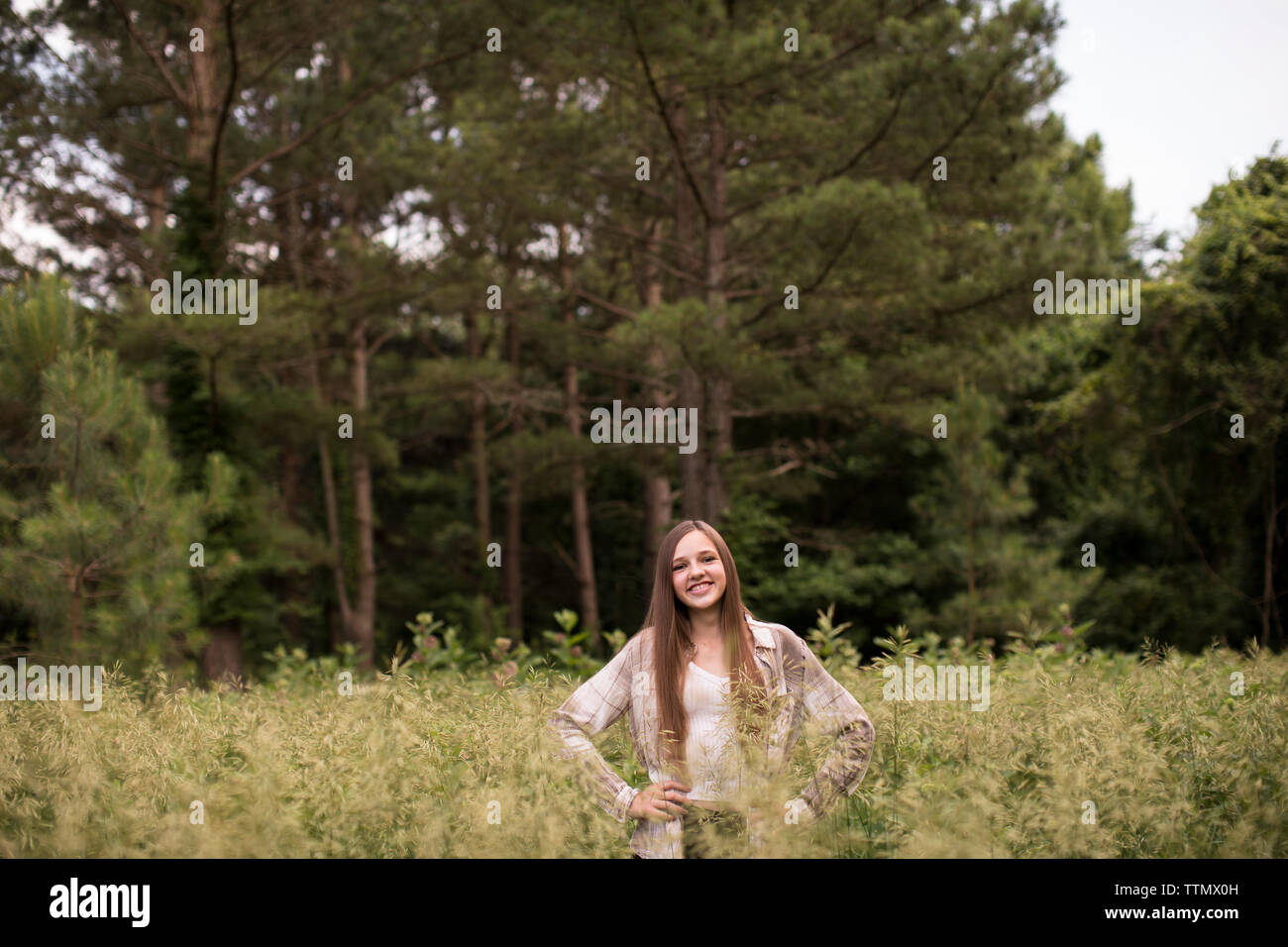 Ampio angolo di fiducioso e sorridente ragazza Teen in piedi in campo verde Foto Stock