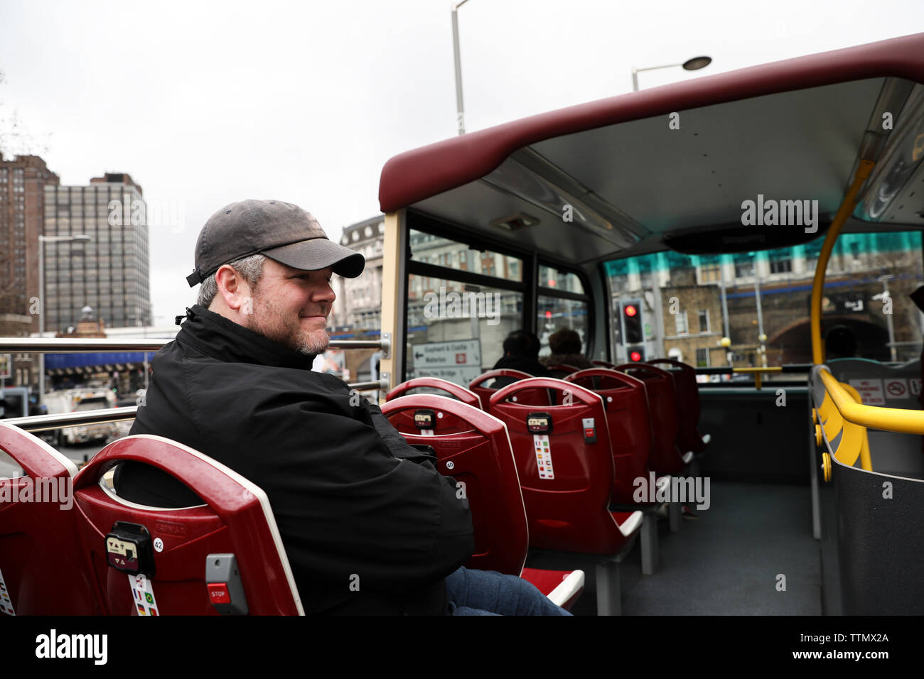 Felice l'uomo in giacca si trova sulla cima del Double Decker Bus in Londra Foto Stock
