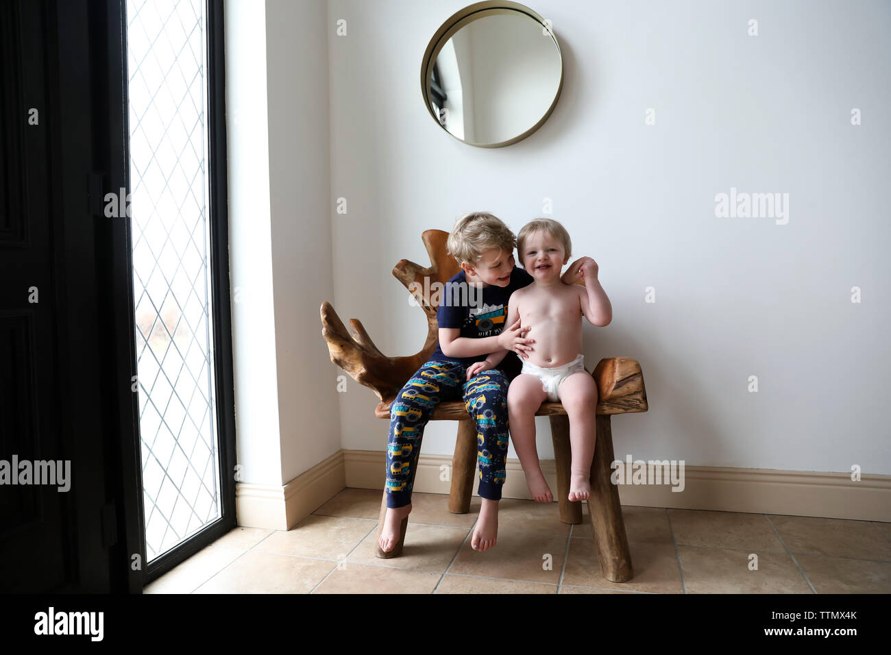 Felice fratelli abbraccio seduti su interni organici panca in legno Foto Stock