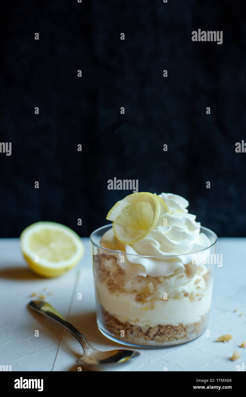 Il dessert con fettina di limone in un contenitore dal cucchiaio sul tavolo Foto Stock