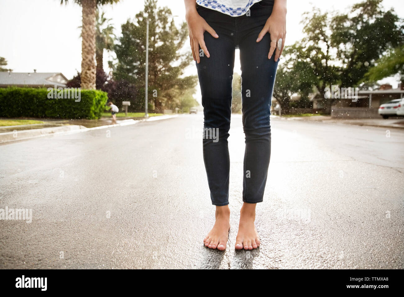 Sezione bassa della donna in piedi su strada bagnata Foto Stock