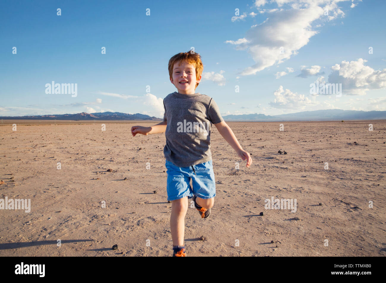 Ritratto di felice ragazzo in esecuzione sul paesaggio arido Foto Stock