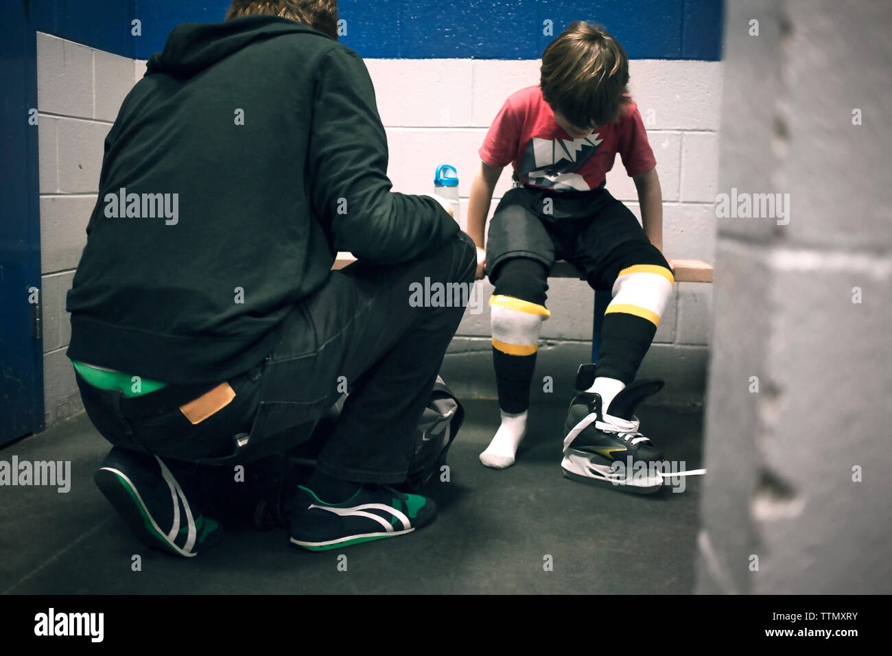 Padre aiutando figlio con pattini da ghiaccio Foto Stock
