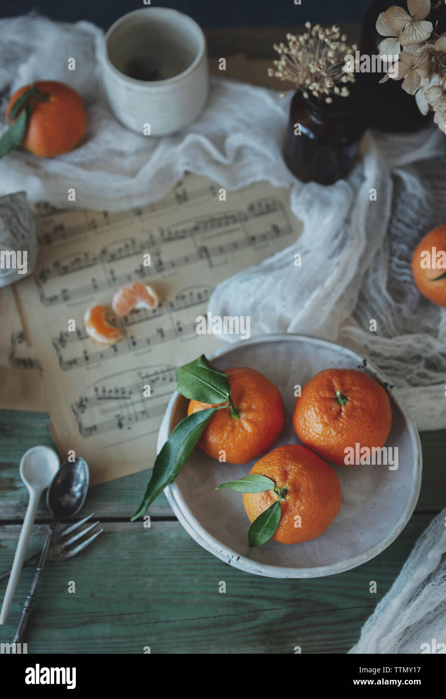 Alcuni mandarini su una piastra sulla parte superiore di un foglio di musica Foto Stock