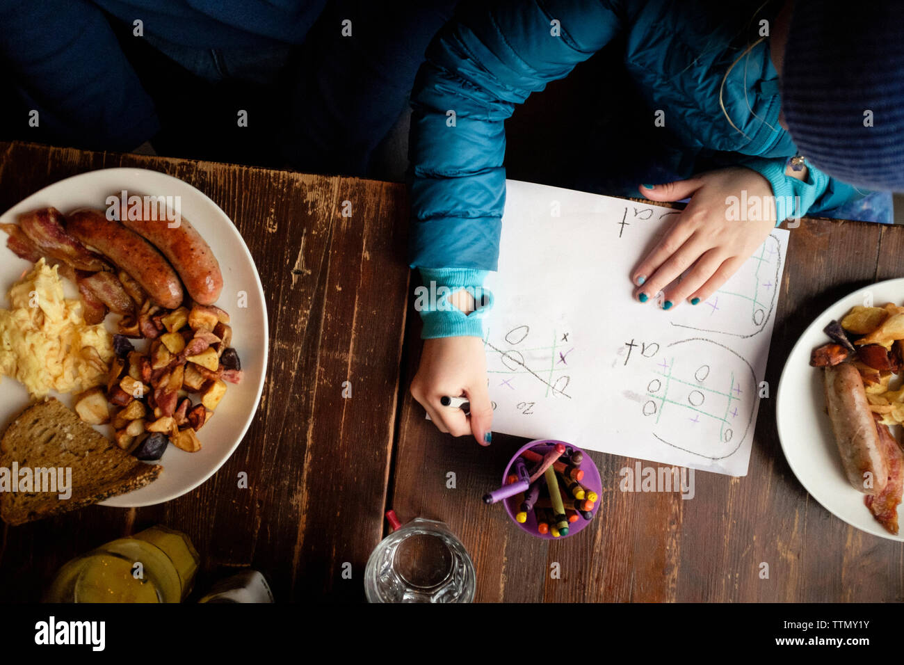 Angolo di Alta Vista della ragazza studiare durante la seduta dal cibo sulla tavola a casa Foto Stock
