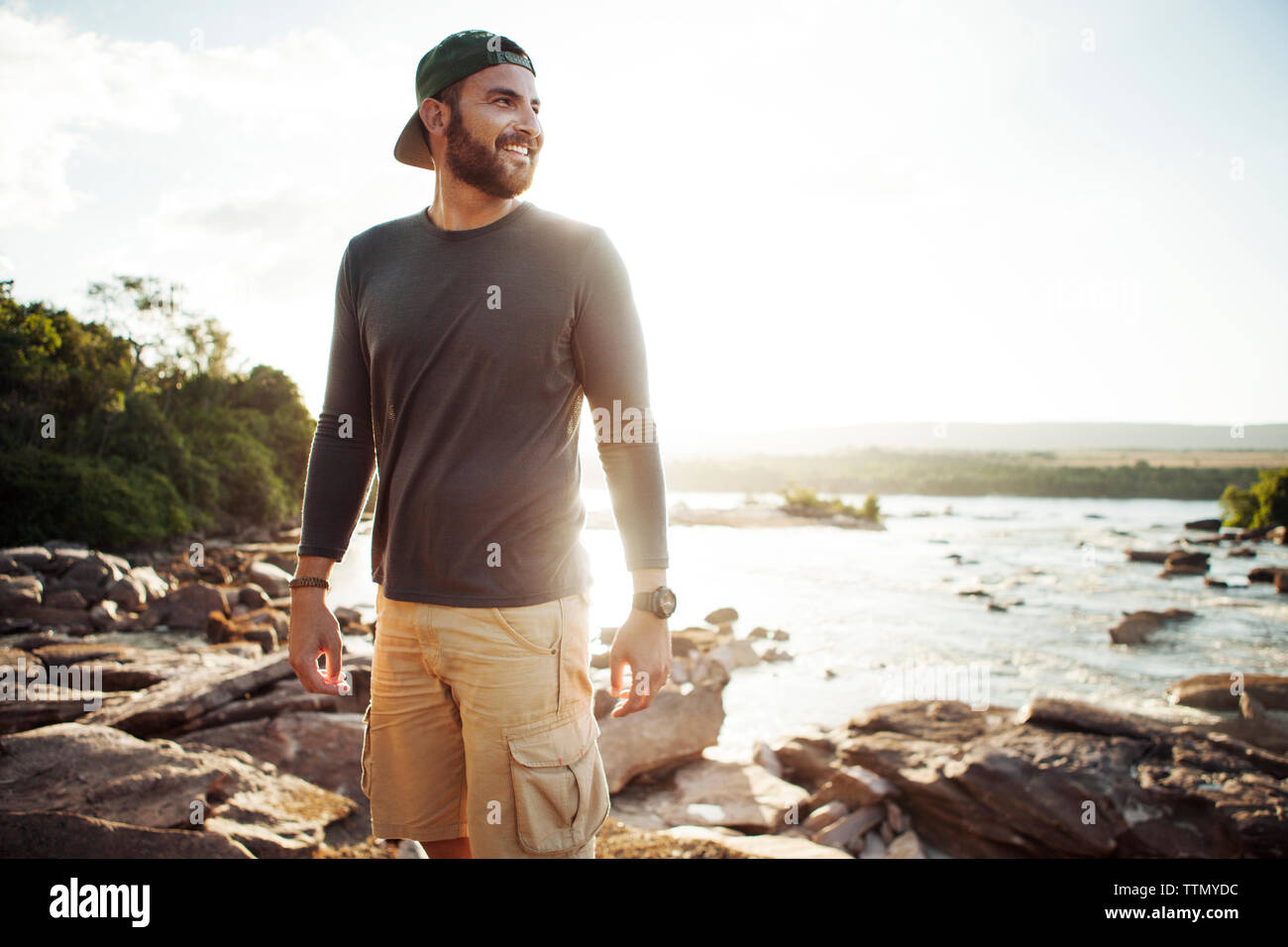 Felice l'uomo che guarda lontano mentre in piedi sul lungolago durante il tramonto Foto Stock