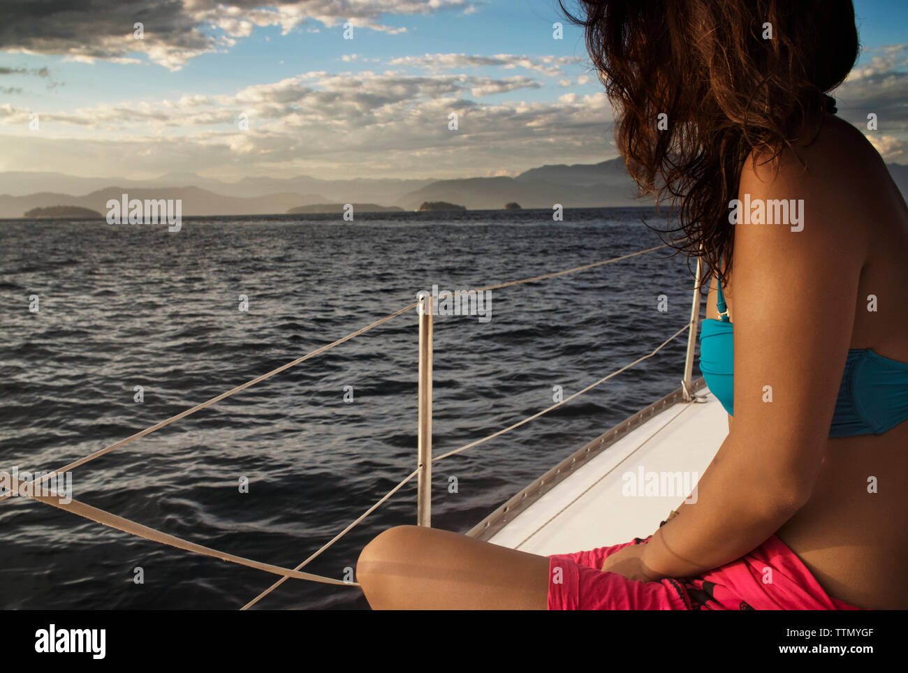 Donna seduta in barca sul mare contro il cielo durante il tramonto Foto Stock