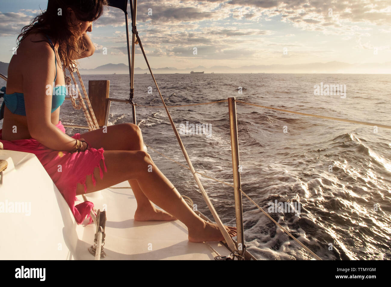 Vista laterale della donna seduta in barca sul mare contro il cielo durante il tramonto Foto Stock