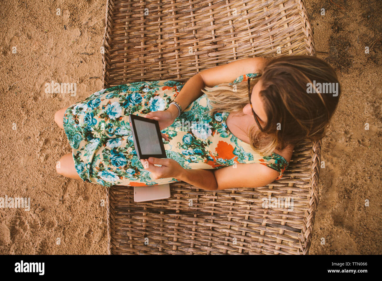 Elevato angolo di visione della donna che utilizza computer tavoletta mentre vi rilassate sulle amache in spiaggia Foto Stock