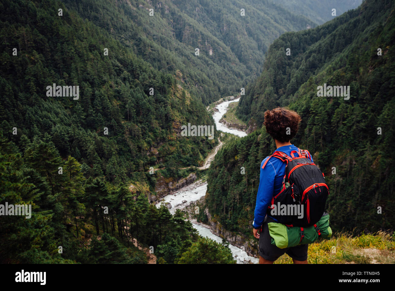 Vista posteriore di un escursionista con zaino cercando di visualizzare mentre si sta in piedi sul monte Foto Stock