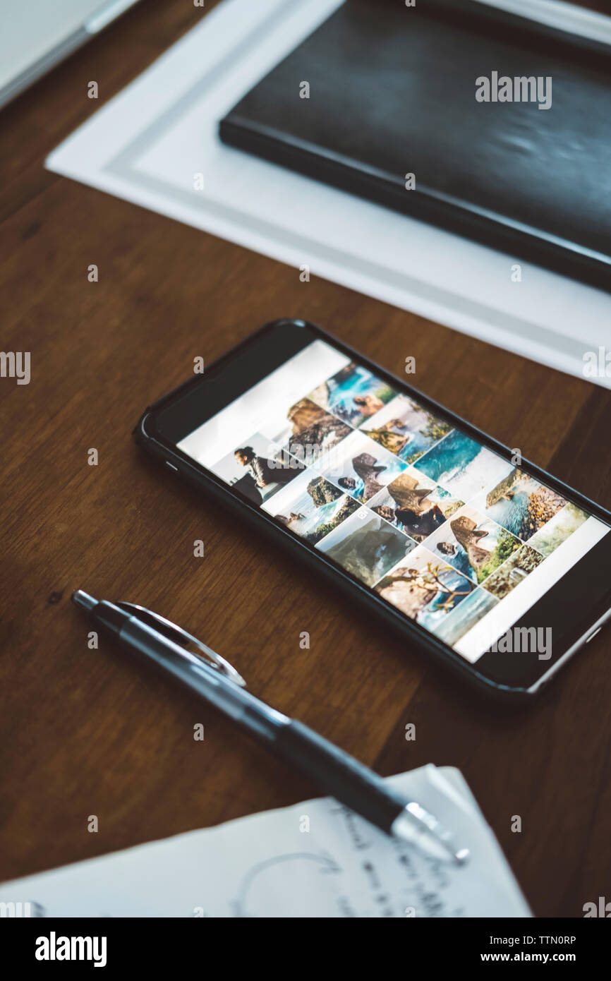 Angolo di Alta Vista del telefono cellulare con penna e diario sul tavolo di legno Foto Stock