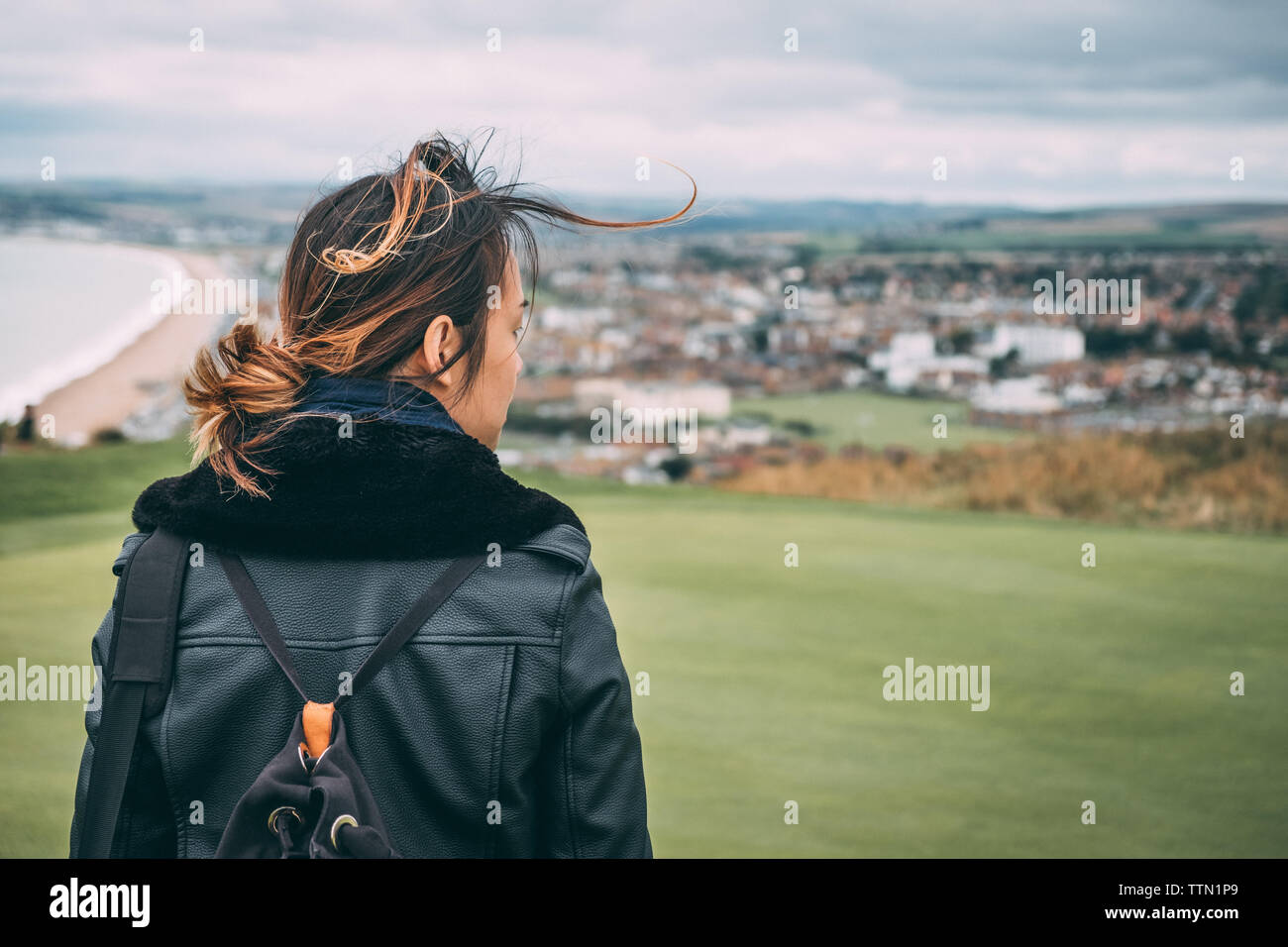 Donna che guarda dalla sommità di una collina al mare in autunno Foto Stock