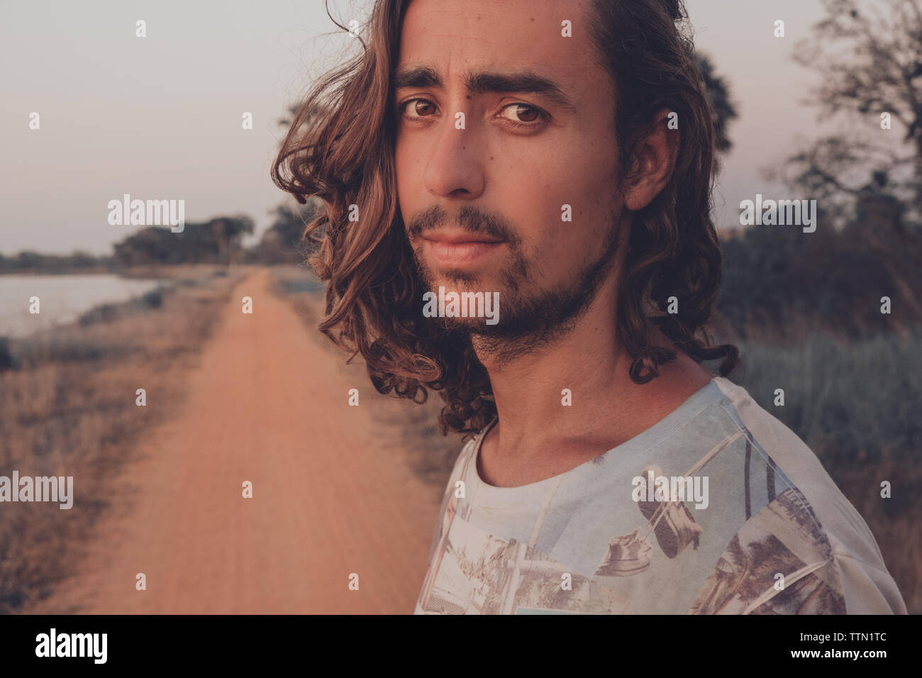Ritratto di un uomo con i capelli lunghi e guardando la telecamera per esterno Foto Stock