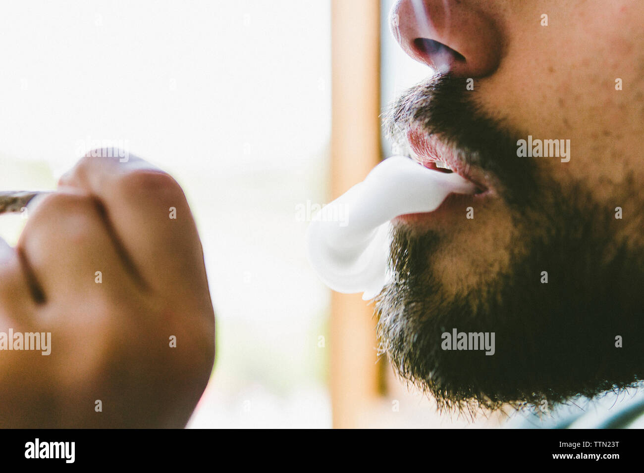 Sezione mediana di uomo barbuto fumare marijuana joint Foto Stock