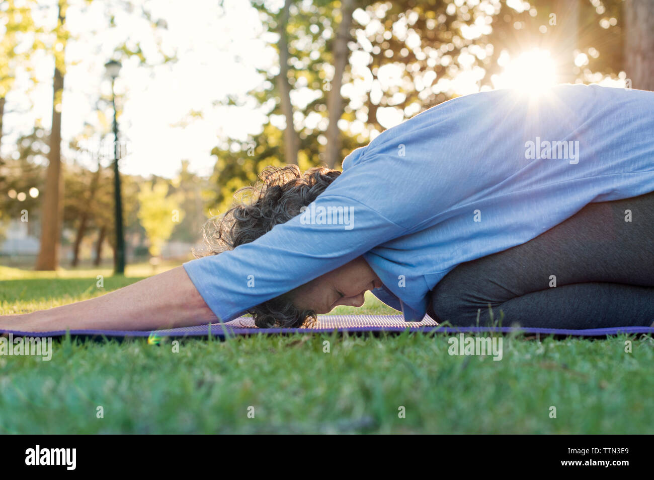 Donna matura fare yoga sul campo erboso Foto Stock