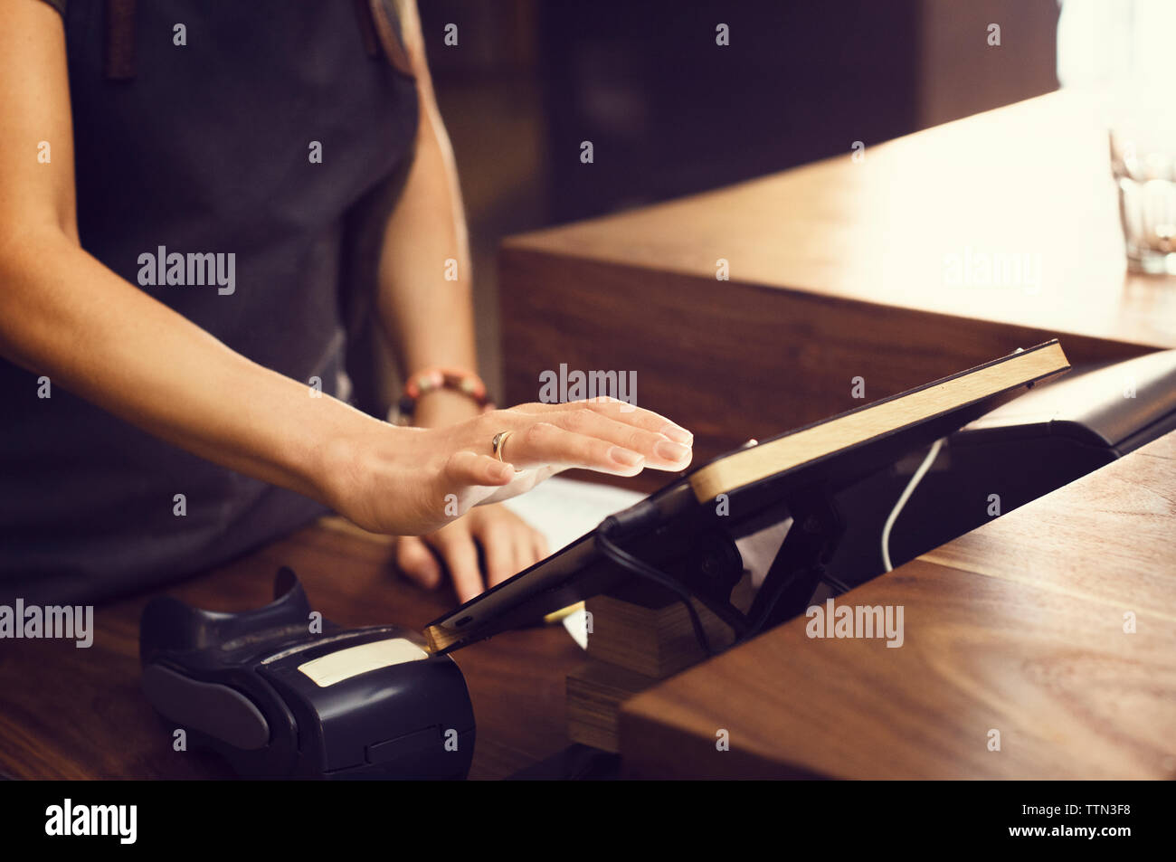 Sezione mediana del proprietario utilizzando tavoletta digitale presso la cassa in coffee shop Foto Stock