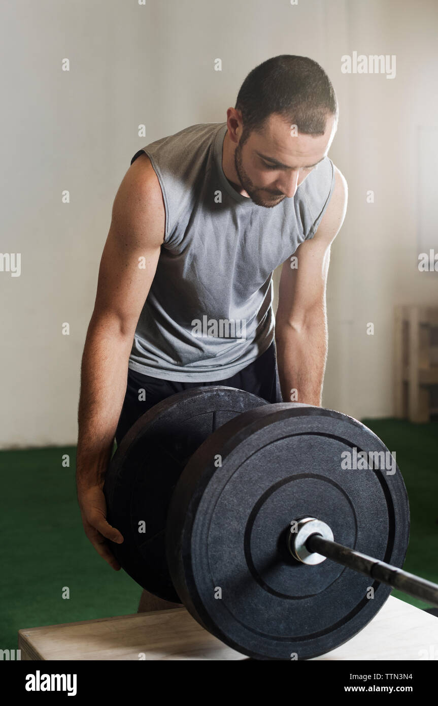 Atleta maschio che fissa barbell in palestra Foto Stock