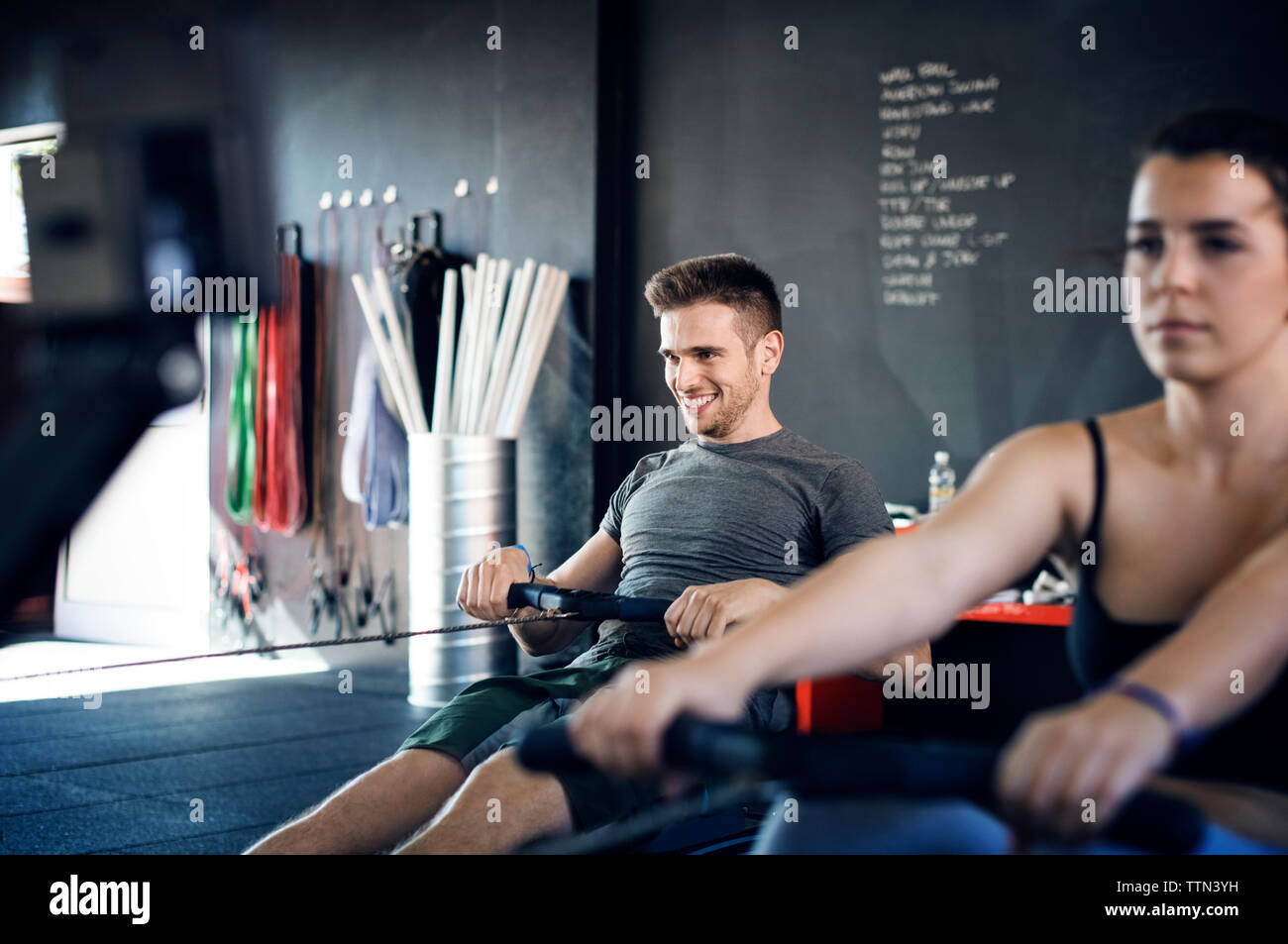 Felice l'uomo esercita sulla macchina di canottaggio in palestra Foto Stock